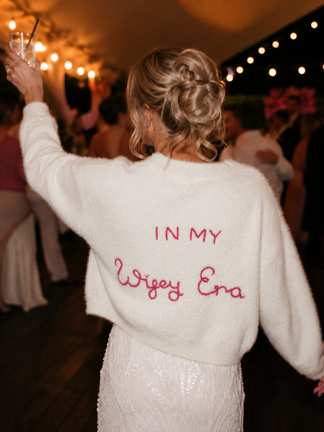 Person wearing a white sweater with red text at a party.